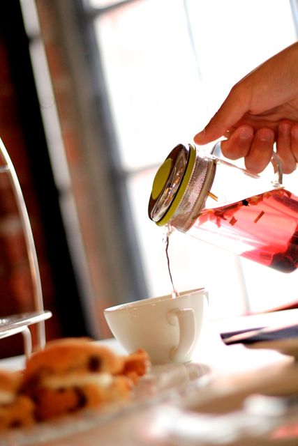 Close-up of Hand Pouring Tea into a Cup with Scones - Download Free Stock Images Pikwizard.com