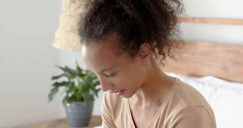 Peaceful Woman Relaxing in Minimalist Bedroom with Potted Plant