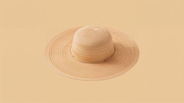 Elegant wide-brimmed straw hat on beige background