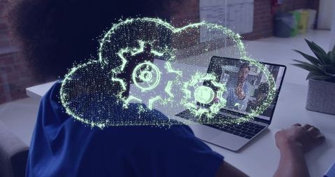 Remote worker using laptop with holographic cloud gears illustrating cloud automation