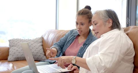 Teenager and Grandmother Bonding Over Laptop at Home