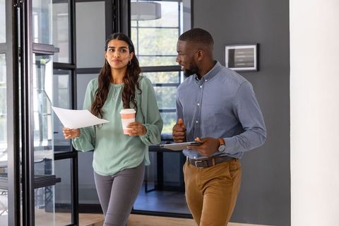 Diverse coworkers discussing work in modern office corridor