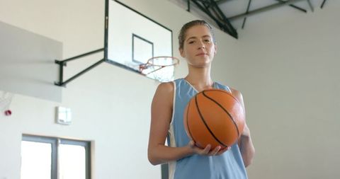 Female Athlete Posing with Basketball in Indoor Arena