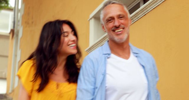 Smiling Couple Walking Along Yellow Wall - Download Free Stock Images Pikwizard.com