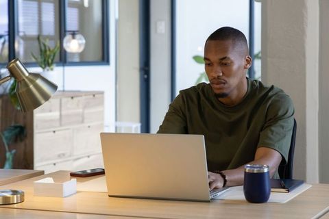 African american man working remotely typing on laptop in modern minimalist office