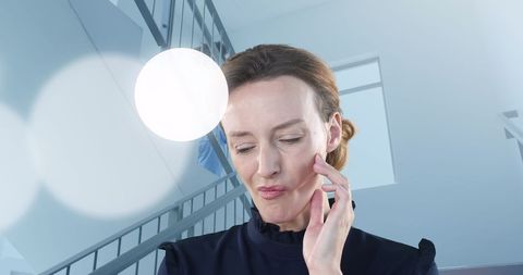 Contemplating woman touching her face on spiral staircase