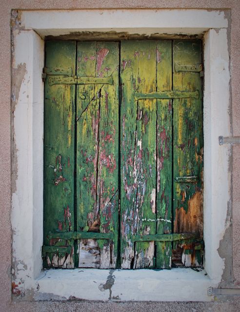Old weathered green wooden shutters with peeling paint on a rustic wall. Ideal for backgrounds, architecture themes, vintage or historical projects, and high-resolution texture needs. Suitable for designers looking for detailed HDR images highlighting decayed material and antique aesthetics.