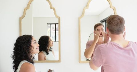 Diverse Couple Enjoying Morning Skincare Routine in Modern Bathroom