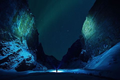 Hiker Stands in Snowy Canyon under Starry Night Sky
