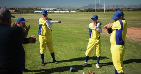 Community cricket team warming up in yellow and blue uniforms on grass field before match