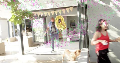 Stepping man holding gold zero balloon into sunlit patio with confetti and pennant garland