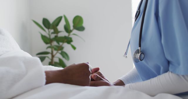 This image depicts a nurse holding a patient's hands, expressing compassion and care. It is perfect for illustrating concepts related to healthcare, patient support, nursing, and medical care in hospitals. Useful for websites, articles, and educational materials about patient care, hospital environments, and nurse responsibilities.