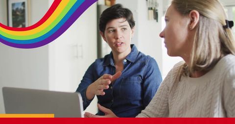 Lesbian Couple Discussing Project with Laptop in Home Workspace
