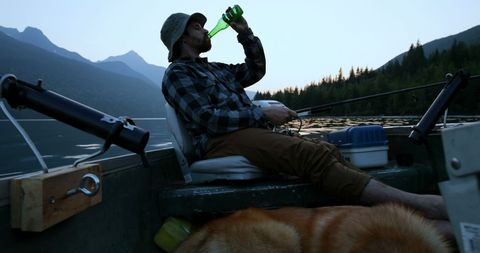 Man Relaxing with Dog on Mountain Lake at Sunset
