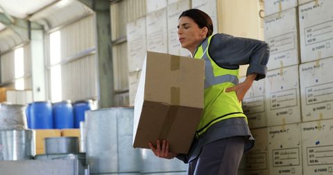 Warehouse Worker Struggles with Back Pain While Lifting Heavy Box - Download Free Stock Images Pikwizard.com