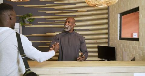 Reception staff greeting visitor in modern office lobby