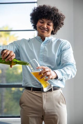 Young man pouring beer from bottle in bright indoor setting