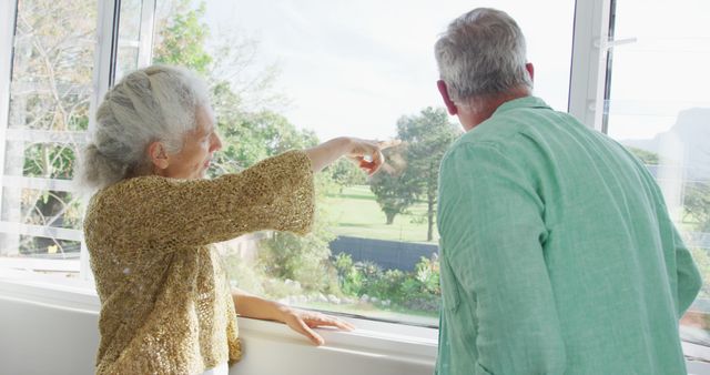 Happy caucasian senior couple standing at window. active and healthy retirement lifestyle at home.