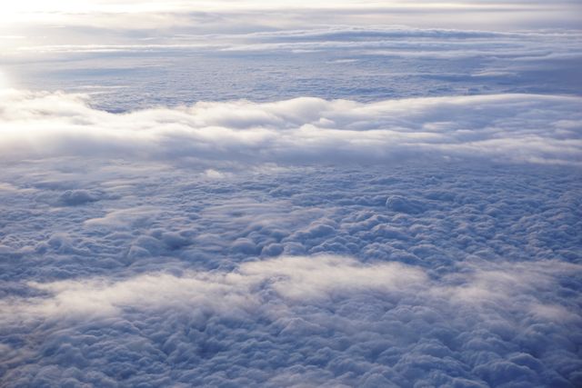 Aerial view of endless cloud layers seen from an airplane, showing the ethereal beauty of clouds from a high altitude. Ideal for travel promotions, inspirational content, background designs, nature-themed publications, and illustrating aviation concepts.