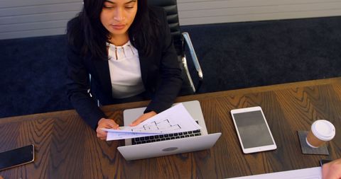 Businesswoman analyzing reports at modern office desk