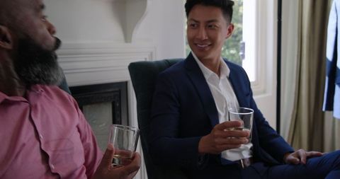 Diverse friends socializing with drinks at home in formal attire