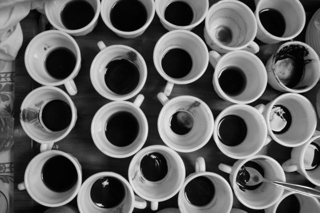 Top view of multiple empty coffee cups arranged in a vibrant abstract pattern, taken in black and white. Suitable for illustrating themes of coffee culture, social gatherings, artistic design, and daily routines. Ideal for use in cafes, art galleries, advertisements, or editorial content involving coffee consumption or artistic expression.