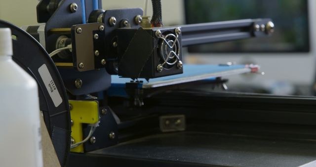 This image shows a close-up of a 3D printer's extruder head while it is at work. The machinery appears to be in the midst of printing a design. Ideal for use in articles, blogs, and marketing materials focused on manufacturing technology, 3D printing innovations, tech equipment, and automated industrial processes.