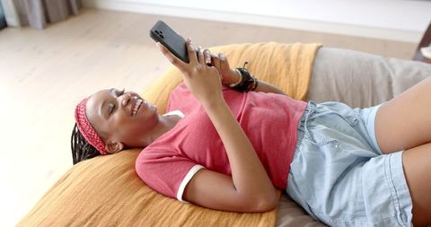 Cheerful Woman Relaxing at Home Using Smartphone