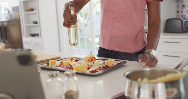 Person sprinkling seasoning on a tray of mixed vegetables and tofu in contemporary kitchen. Perfect for promoting healthy eating, food blogs, cooking tutorials, and kitchen appliance advertisements.