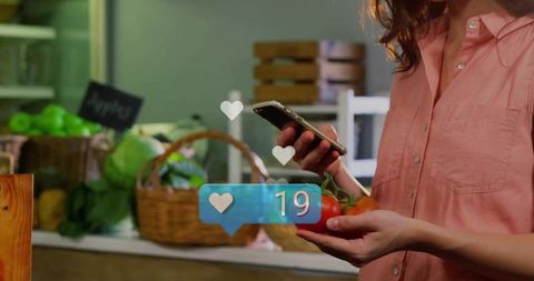 Woman holding tomatoes tapping smartphone at farmers market with social like overlay