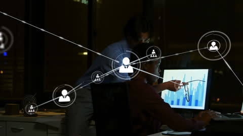 Business Professionals Analyzing Data with Technology Interfaces at Night