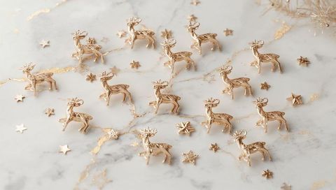 Scattered gold reindeer ornaments decorating marble tabletop for elegant holiday styling