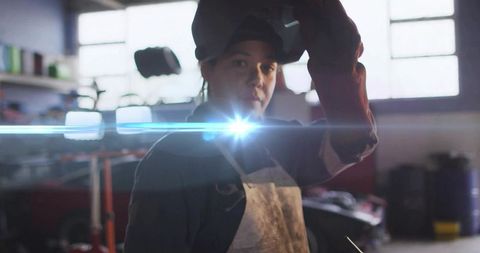 Female Welder Lifting Visor in Garage Workshop