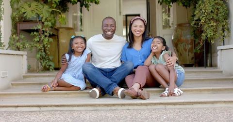 Happy Family Sitting on Porch Steps Enjoying Quality Outdoors Time