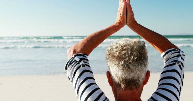 Ideal for topics on senior health, beach yoga practices, mindfulness routines in nature, and promoting wellness and relaxation in older adults. Suitable for illustrating the importance of physical fitness and mental serenity for the elderly.