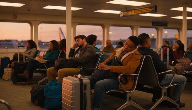 Tired travelers resting at busy airport gate during sunset with luggage and backpacks