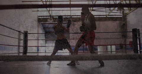 Female boxers sparring in industrial warehouse gym backlit silhouettes low-angle action