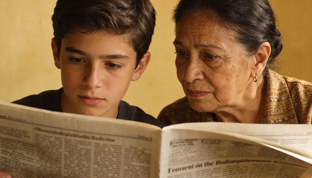 Grandmother and grandson reading broadsheet in warm cozy home, intimate family moment