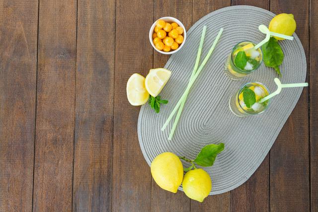 Glass of mojito cocktail, lemon and yellow cherries on the wooden board