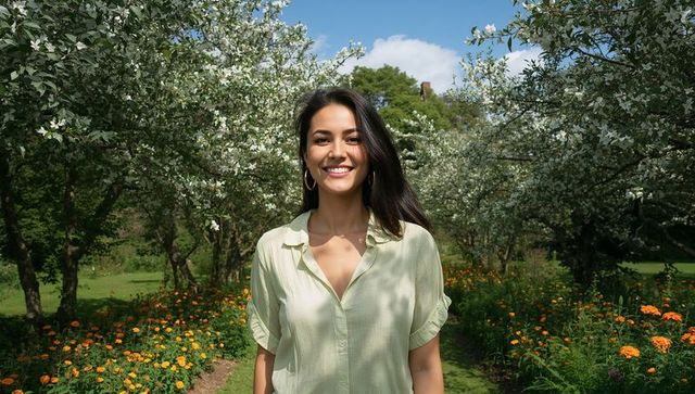 Smiling Woman Strolls Through Idyllic Flower-Lined Orchard Path in Spring