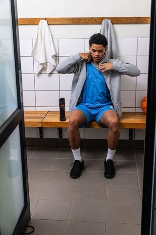 Teen basketball player adjusts hoodie in locker room