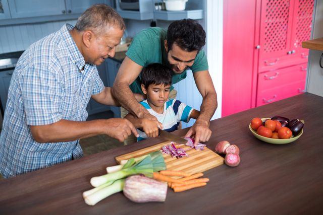 Smiling man looking at boy cutting onion with father in kitchen at home