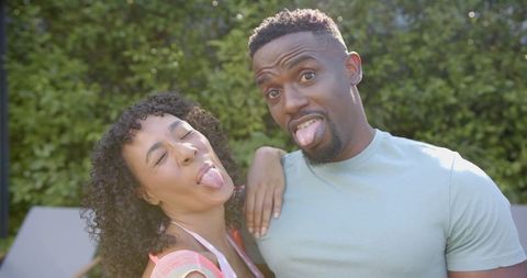 Playful couple making funny faces outdoors in sunny weather