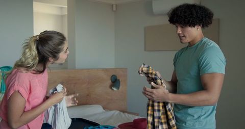 Young Couple Packing Suitcase for Vacation Together in Bedroom
