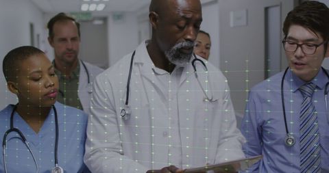 Diverse Medical Team Reviewing Digital Data in Hospital Corridor