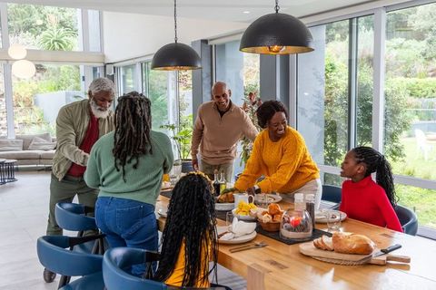 Multigenerational african american family gathering around dining table sharing meal in modern home