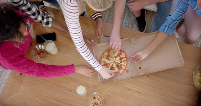 Group of friends sharing pizza; their hands reach for slices, suggesting enjoyment. Ideal for content about socializing, friendship, casual dining. Useful for marketing campaigns promoting food delivery, restaurants or social dining experiences.