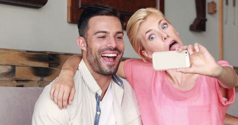 Playful Couple Taking Selfie in Living Room with Joyful Expressions