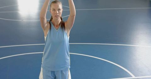 Female basketball player reaching for jump shot on glossy blue indoor court