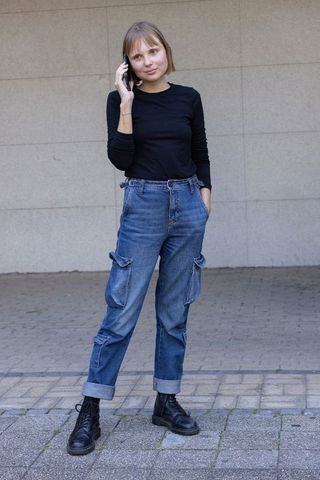 Young woman talking on phone wearing cargo jeans and black boots in urban minimal style